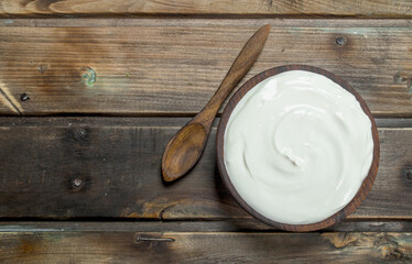 Fresh sour cream in bowl with spoon .