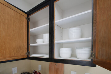 Fototapeta na wymiar A view of content inside a kitchen cabinet area, featuring several white dishware.