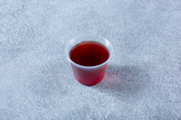 Obraz na płótnie Canvas A view of a plastic condiment cup of red vinaigrette.