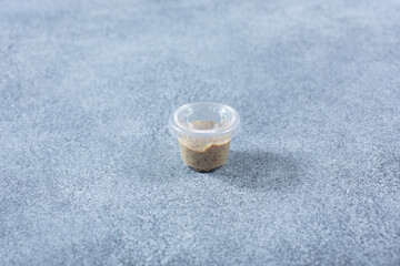 A view of a closed condiment cup of whole ground mustard.