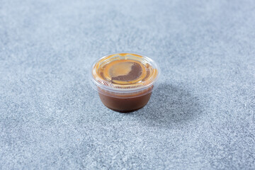 A view of a closed plastic condiment cup of balsamic vinaigrette dressing.