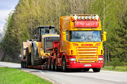 Colorful customized Scania G580 Truck Hauls Cat Wheel Loader on Semi Trailer as Oversize Load. 