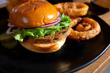 A view of a vegan burger, with a side of onion rings.