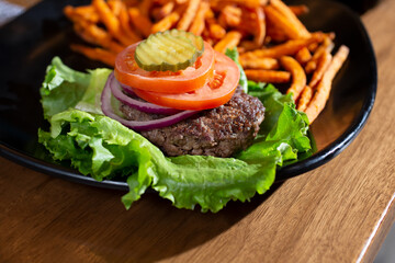 A view of a protein style hamburger, with a side of sweet potato fries.