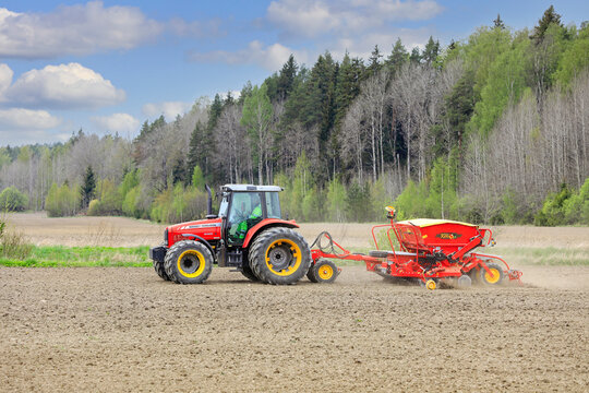 Massey Ferguson Tractor and Seeder Working in Field on a Day of Spring. Copy Space. 