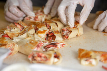 A view of a cook preparing a catering tray full of chicken shawarma wrap slices, seen at the ingredient station of a local Lebanese restaurant.