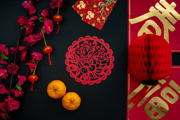 Chinese lunar new year decoration over black background. Flat lay concept with tangerine and festive decoration. Translation for word on decoration means Blessing and Spring.