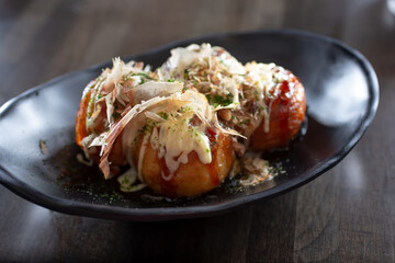 A view of a plate of takoyaki, which is Japanese deep fried octopus meat balls.
