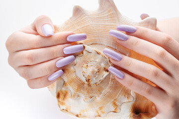 Obraz na płótnie Canvas Hand with long violet manicured nails and seashell