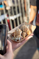 A view of an foodie influencer taking a social media photo of a Japanese street food called takoyaki.