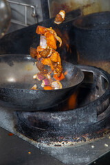 A view of a shaken beef tossed in a wok, in a restaurant kitchen setting.