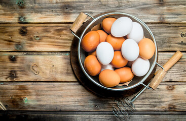 Eggs in a saucepan with a whisk.