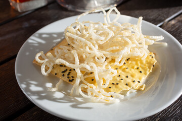 A view of a plate of deep fried rice noodles and rice cracker.