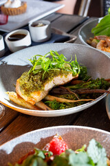 A view of a plate of pesto crusted salmon filet.