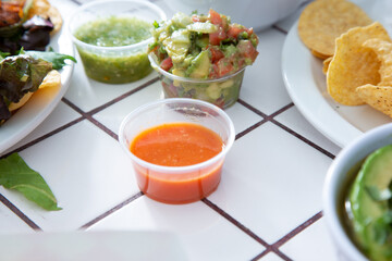 A view of several varieties of salsas, featuring habanero, guacamole, and verde.