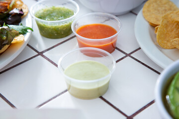 A view of a variety of salsas in plastic condiment cups.