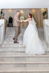 Naklejka premium The bride and groom in a wedding dress on the stairs.