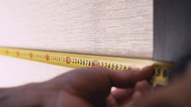 measuring the wall with a tape measure.