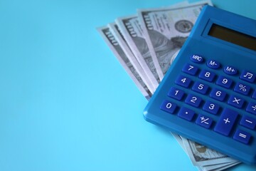 Blue calculator and money on blue background with copy space