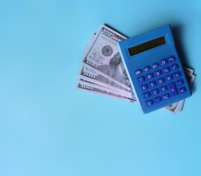 Blue calculator and money on blue background with copy space