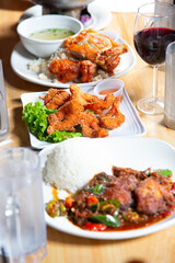 A view of several pan Asian entrees, featuring crispy Hainan chicken, coconut shrimp, and spicy chili beef.
