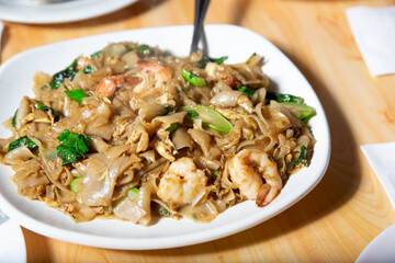 A view of a plate of pad see ew, with shrimp.