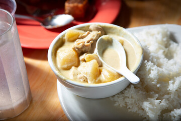 A view of a bowl of yellow curry, with a side of rice.