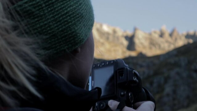 Close up of woman taking pictures of beautiful mountain landscape in the morning -rear view in slow motion