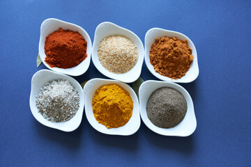 Spices close-up in bowls on a blue background. 