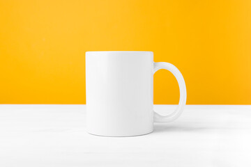 White ceramic mug with blank copy space front view. Cup mockup for advertising and logo on a wooden table.