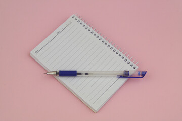 Blank notepad with pen on pink background
