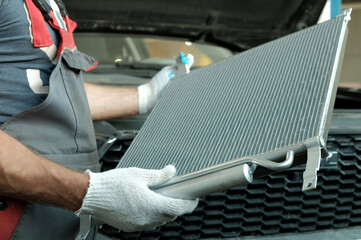 Spare parts for the car. Engine cooling radiator. An auto mechanic inspects a new radiator before...