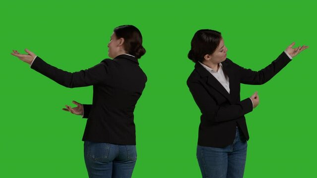 Corporate worker creating new advertisement on camera, pointing sideways to show ad icon or example in studio. Young office employee wearing formal suit expressing advertising gesture.