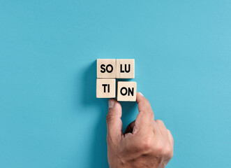 Finding a solution to a problem in business. Male hand placing wooden blocks into a square shape to...