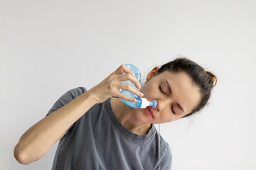 Girl rinses her nose with saline solution at home Using Neti Pot. Treatment and prevention of colds. How to rinse your nose when you have a runny nose. - obrazy, fototapety, plakaty