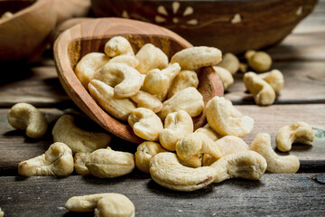 Cashews in a bowl with a wooden scoop.