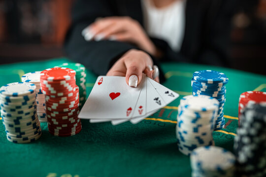 female hand takes poker chips from a pile at a round poker table. risky bets in poker