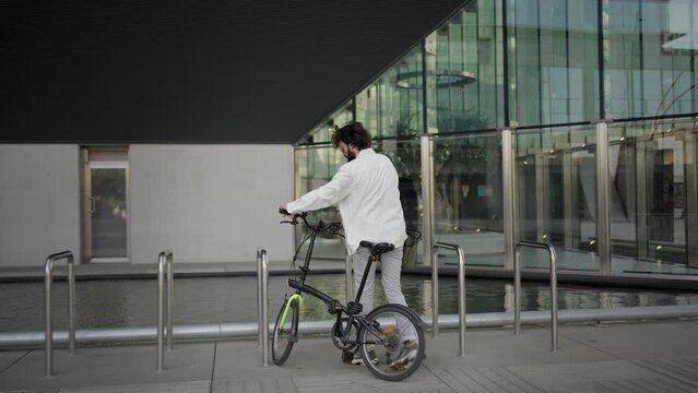 Young freelancer professional man riding bike going to work in the city 