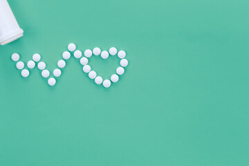 Scattered heart shaped pills on green background, flat lay.