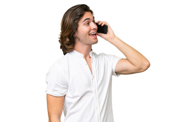 Young caucasian man isolated on green chroma background keeping a conversation with the mobile phone