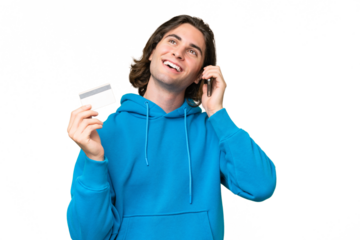 Young handsome man isolated on green chroma background keeping a conversation with the mobile phone and holding a credit card