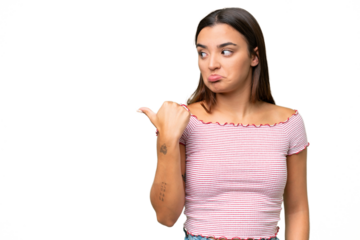 Young caucasian woman isolated on green chroma background unhappy and pointing to the side