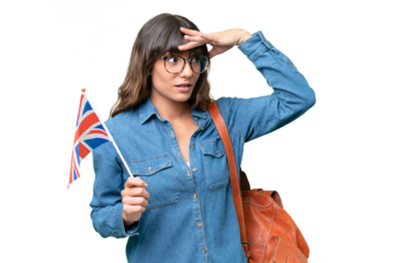 Young caucasian woman holding an United Kingdom flag over isolated background doing surprise gesture while looking to the side