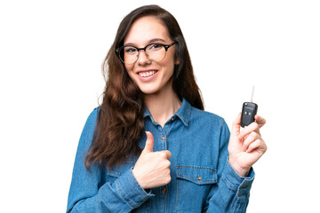 Young caucasian woman holding car keys over isolated background with thumbs up because something...
