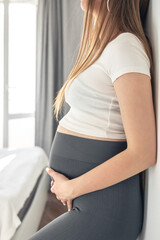 Pregnant woman in the interior of the room on a blurred background.