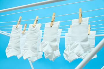 White socks hanging on drying rack on blue background