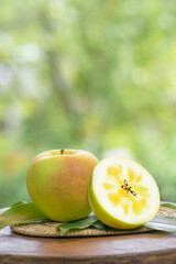 Fresh Green Honey core Apple in wooden basket, Golden Green Meigetsu apple in the basket over green natural Blur background.