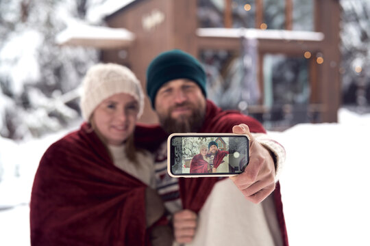 Caucasian couple making selfie in front of house in winter season
