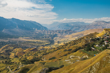 Snow-capped mountains and autumn fields. Beautiful mountain landscape in winter. Panoramic view, Dagestan, Russia.