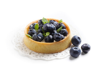 Blueberry tart with fresh mint leaves at white background, top view. French dessert with berries.
